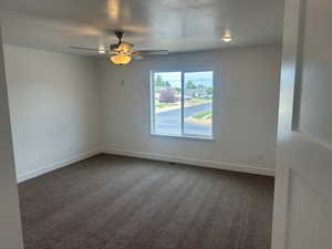 Carpeted empty room with a textured ceiling and ceiling fan