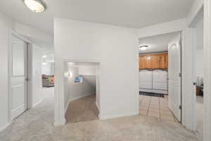 Corridor featuring washer and clothes dryer and light colored carpet