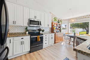 Kitchen with vaulted ceiling, an inviting chandelier, stainless steel appliances, and dark stone counters