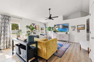 Living room with lofted ceiling, ceiling fan, and light hardwood / wood-style floors