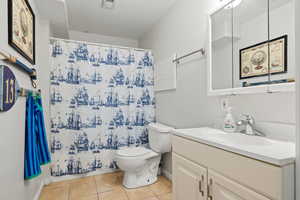 Bathroom featuring tile patterned floors, walk in shower, toilet, and vanity