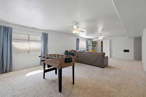 Rec room featuring ceiling fan, a wealth of natural light, and light carpet