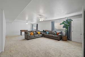 Living room featuring ceiling fan, a textured ceiling, and carpet floors