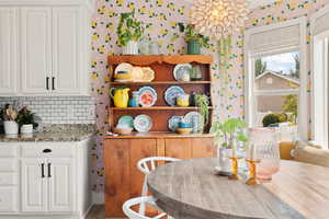 Kitchen with light stone counters, white cabinets, and decorative backsplash