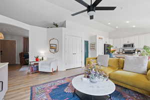 Living room with lofted ceiling, ceiling fan, sink, and light wood-type flooring