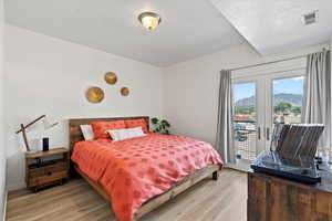 Primary Bedroom with french doors, a mountain view, light hardwood / wood-style floors, access to outside, and a textured ceiling