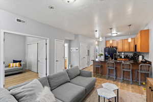 Living room with a textured ceiling, sink, and light hardwood / wood-style floors