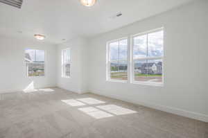 Spare room with a wealth of natural light and light carpet