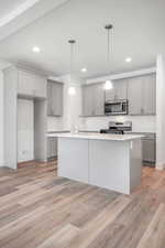 Kitchen with a center island with sink, stainless steel appliances, gray cabinetry, and light wood-type flooring