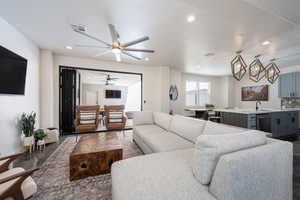 Living room featuring ceiling fan with notable chandelier and sink