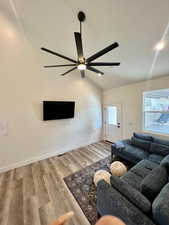 Living room featuring light hardwood / wood-style flooring, ceiling fan, and vaulted ceiling