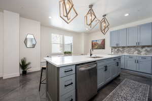 Kitchen with a kitchen island with sink, pendant lighting, tasteful backsplash, a kitchen bar, and stainless steel dishwasher