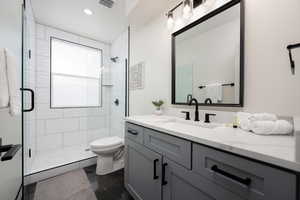 Bathroom featuring vanity, toilet, and an enclosed shower