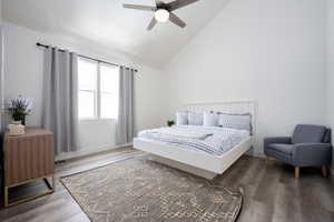 Bedroom with dark hardwood / wood-style flooring, ceiling fan, and lofted ceiling