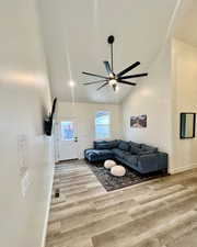 Living room with high vaulted ceiling, ceiling fan, and light wood-type flooring