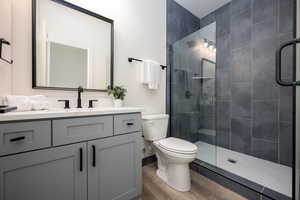 Bathroom with toilet, hardwood / wood-style flooring, walk in shower, and vanity