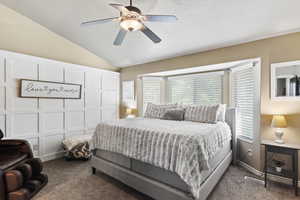 Carpeted bedroom featuring vaulted ceiling and ceiling fan