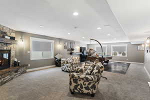 Living room featuring pool table, light colored carpet, and a stone fireplace