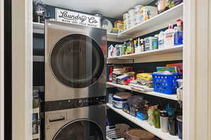 Laundry area with a textured ceiling, stacked washer and dryer, and tile patterned floors