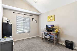 Office area featuring carpet and vaulted ceiling