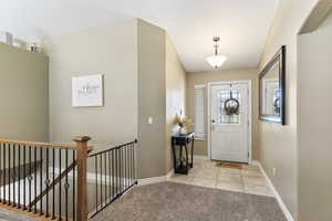 Carpeted foyer entrance featuring vaulted ceiling