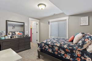 Bedroom featuring light carpet and a textured ceiling