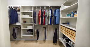 Walk in closet with hardwood / wood-style floors