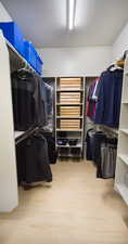 Spacious closet with light hardwood / wood-style flooring