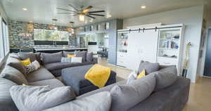 Living room featuring light wood-type flooring, ceiling fan, and a barn door