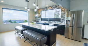 Kitchen featuring hanging light fixtures, light hardwood / wood-style flooring, appliances with stainless steel finishes, sink, and a kitchen island