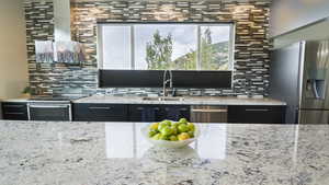 Kitchen featuring sink, stainless steel appliances, light stone countertops, and decorative backsplash