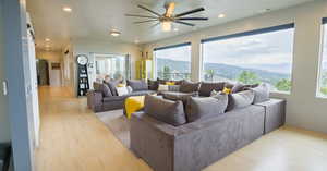 Living room featuring a mountain view, light wood-type flooring, and ceiling fan