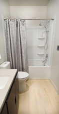 Full bathroom featuring shower / bath combination with curtain, toilet, hardwood / wood-style flooring, and vanity