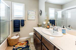 Full bathroom featuring vanity, toilet, plenty of natural light, and bath / shower combo with glass door