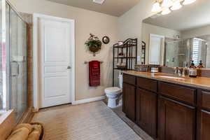 Bathroom with vanity, toilet, an enclosed shower, and tile patterned floors