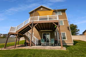 Back of property featuring a wooden deck, a lawn, and a patio area