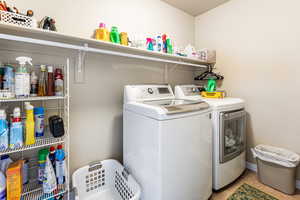 Clothes washing area featuring independent washer and dryer and light tile patterned floors