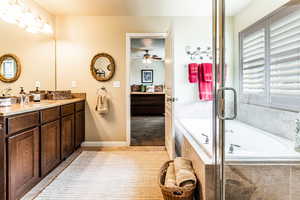 Bathroom featuring tile patterned flooring, vanity, tiled tub, and ceiling fan