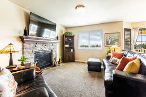 Carpeted living room featuring a wealth of natural light and a stone fireplace