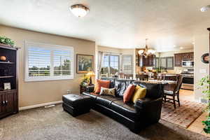 Living room featuring a textured ceiling, light wood-type flooring, and a chandelier