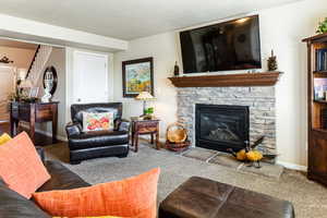 Living room with a stone fireplace and light carpet