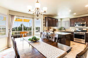 Kitchen with decorative light fixtures, stainless steel appliances, an inviting chandelier, sink, and dark brown cabinetry