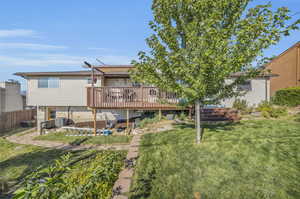 Rear view of property with a wooden deck and a lawn