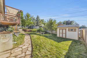 View of flagstone path with a wooden deck and a storage shed