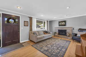 Living room with a gas fireplace, ornamental molding, a wealth of natural light.