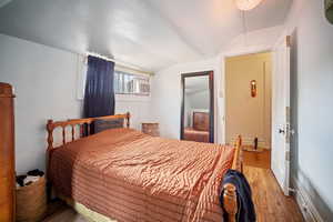 Bedroom featuring lofted ceiling and hardwood / wood-style flooring