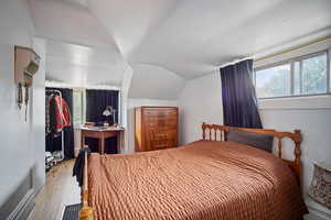 Bedroom featuring light wood-type flooring, multiple windows, and vaulted ceiling