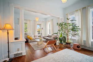 Living room featuring dark hardwood / wood-style floors, a chandelier, and decorative columns