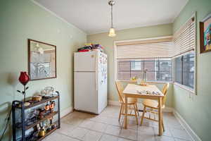 Tiled dining space featuring crown molding