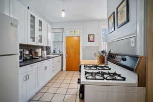 Kitchen featuring white cabinetry, pendant lighting, white appliances, and light tile patterned flooring